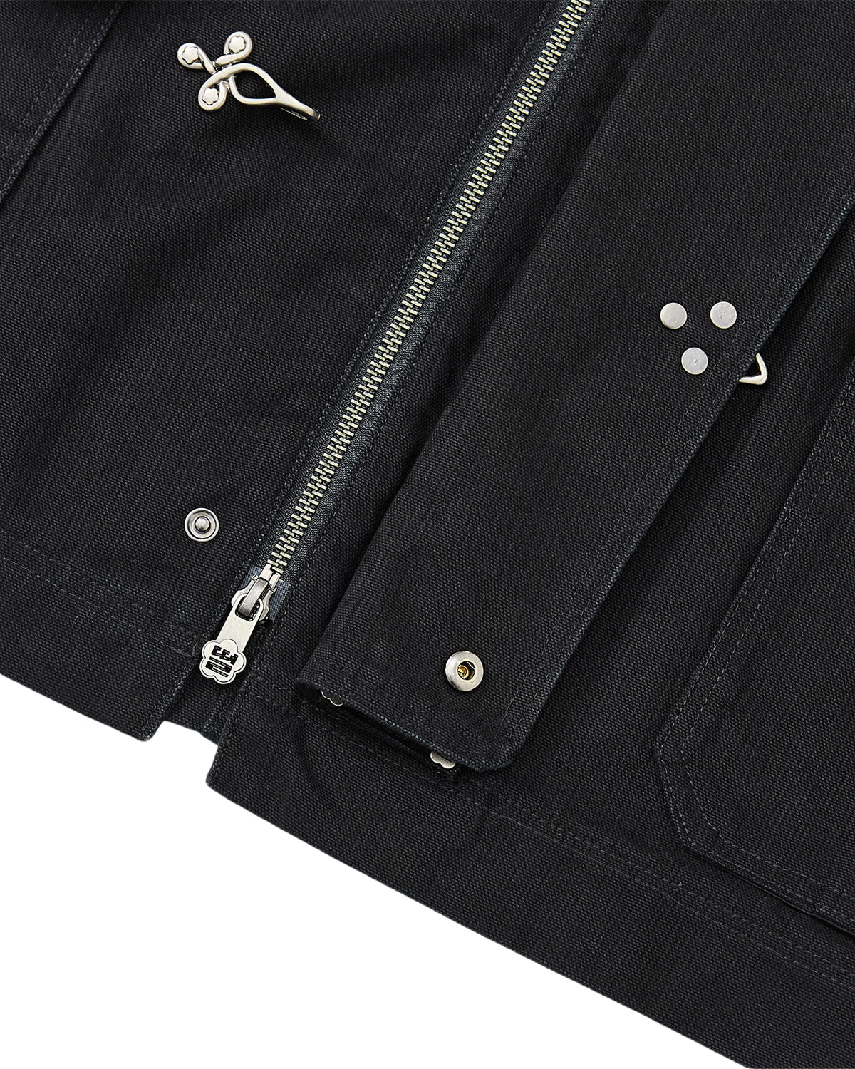 Close-up of the BLACK FIREMAN CLASP JACKET by Sundae School, showcasing its silver zipper, metallic snap buttons, and signature Mochi Floral clasps alongside decorative metal pins. The image highlights the detailed stitching, textured fabric, and subtle vintage-inspired finish.