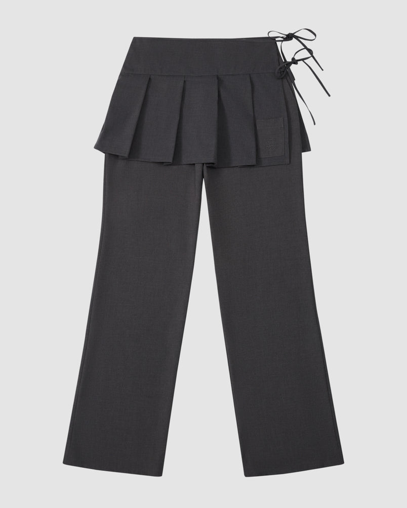 The Sundae School FLARE SKIRT PANTS are black tailored summer wool trousers with a wide waistband, removable pleated skirt overlay, and right side tie detail, shown on a light gray background.