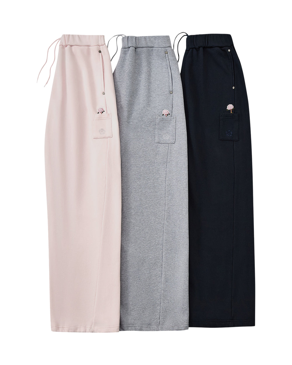 Three HEATHER GREY WRAP SWEATBAJI skirts by Sundae School—one each in pink, gray, and black—are laid side by side. Each features a drawstring waist, a side patch pocket, and is adorned with a small Korean embroidery design on the pocket.