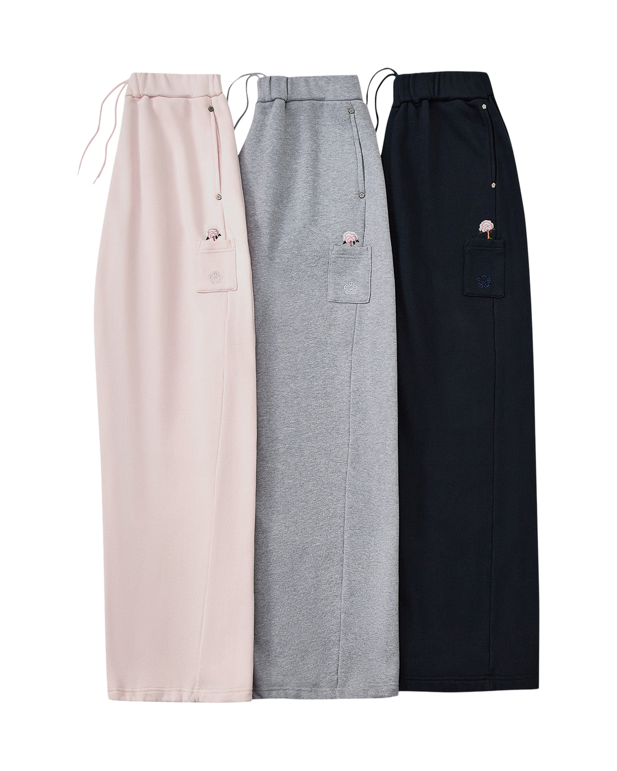 Three HEATHER GREY WRAP SWEATBAJI skirts by Sundae School—one each in pink, gray, and black—are laid side by side. Each features a drawstring waist, a side patch pocket, and is adorned with a small Korean embroidery design on the pocket.