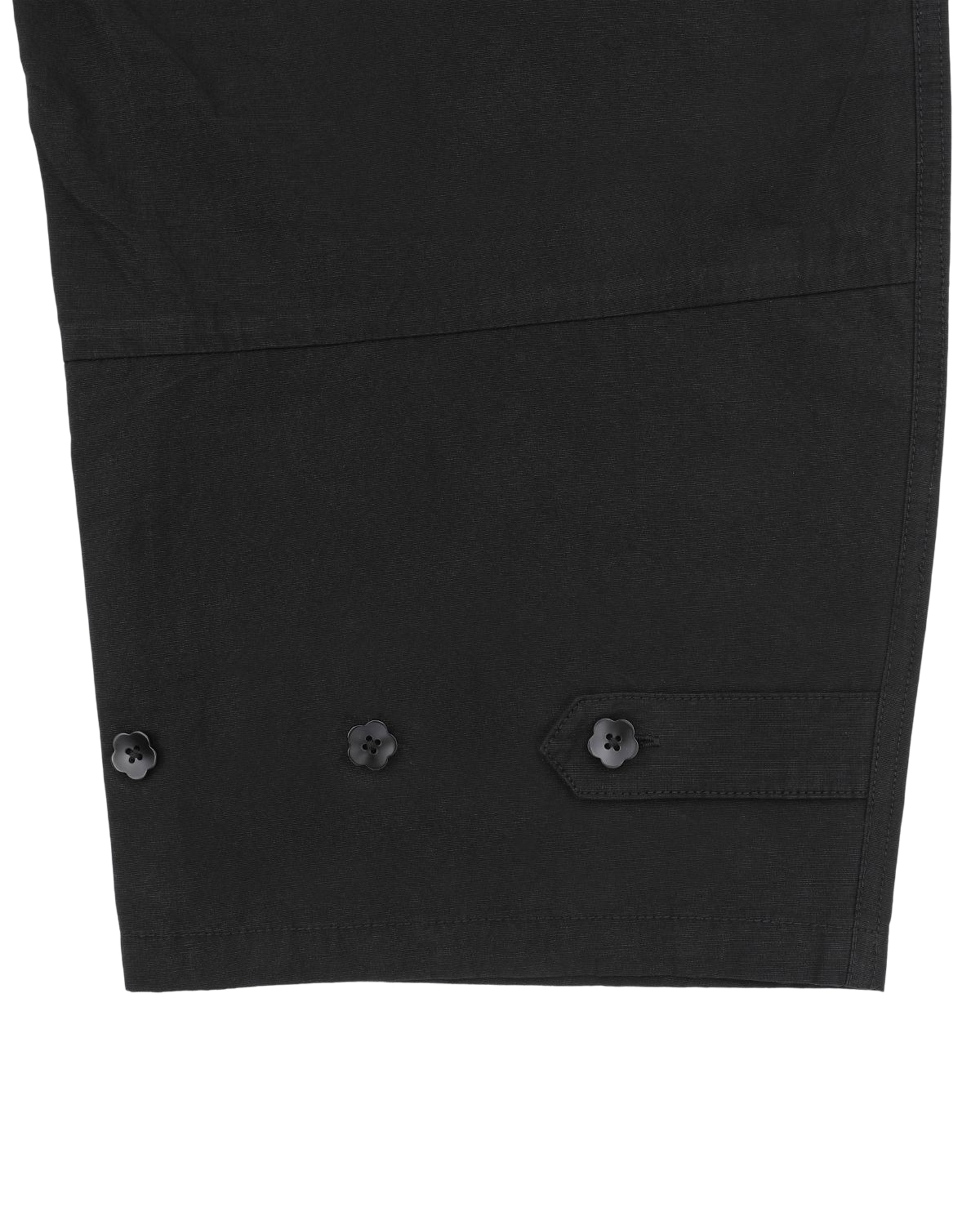 A close-up view of the BLACK FLOWER NORIGAE LINEN TROUSERS by Sundae School, highlighting the black linen fabric with three matching buttons and visible stitching details that showcase subtle Korean-inspired design elements.