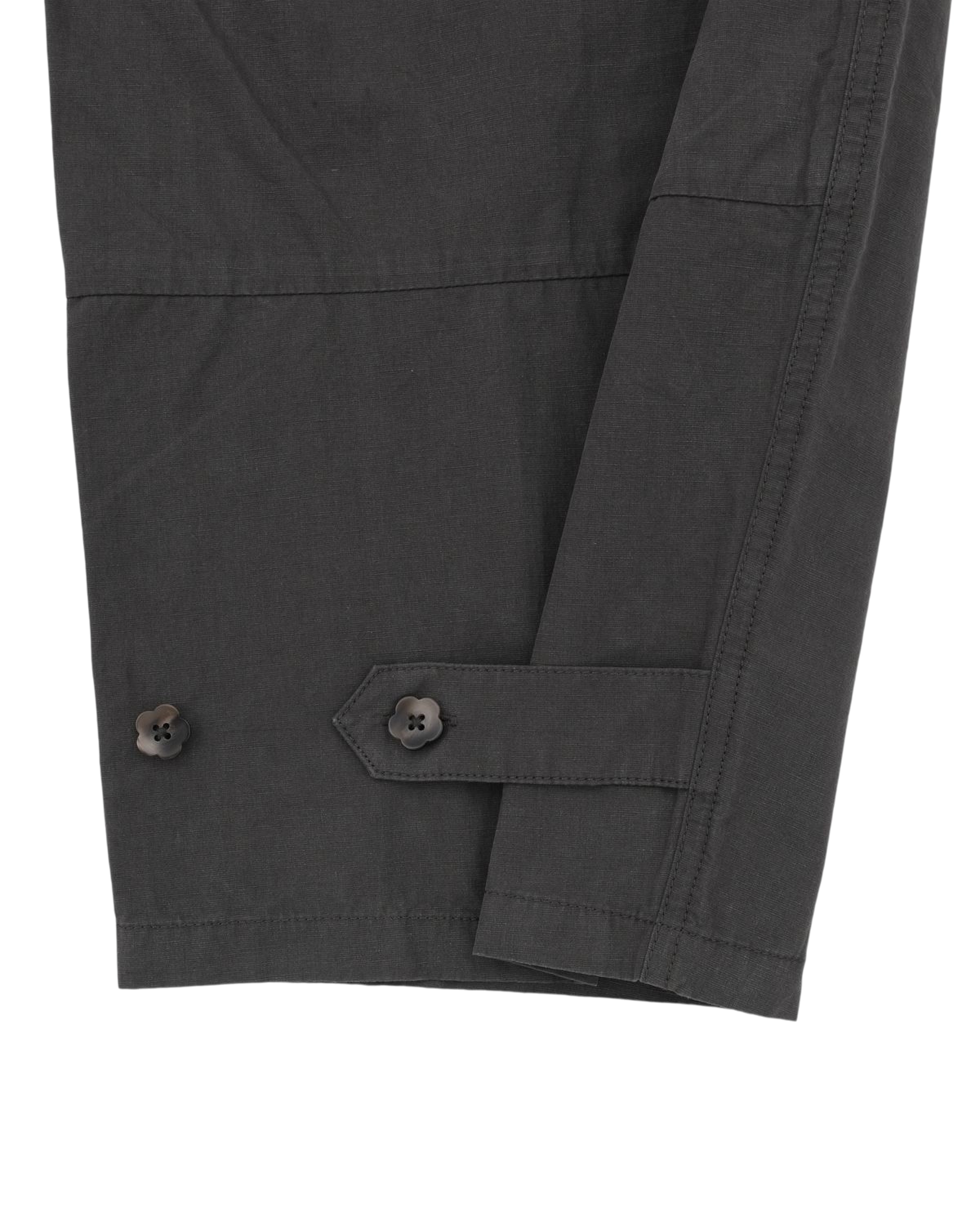Close-up of a dark gray long sleeve with two black buttons and a stitched strap detail near the cuff, displayed against a white background—perfectly paired with Sundae School’s CHARCOAL FLOWER NORIGAE LINEN TROUSERS for a refined, contemporary look.