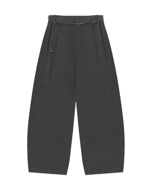 The CHARCOAL FLOWER NORIGAE LINEN TROUSERS by Sundae School are wide-leg black cotton-linen pants featuring pleats, a high waist, and a decorative thin norigae belt with a small knotted accent. Made from soft, slightly textured fabric, these trousers offer a relaxed, modern fit.