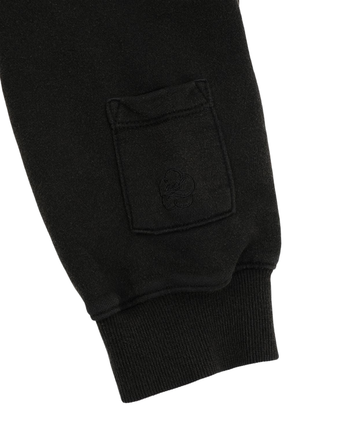 Close-up of the BLACK WASH FLOWER KNOT ZIP UP by Sundae School, showcasing the black cotton sleeve with a small pocket and subtle Hangul Sundae School embroidery above the ribbed cuff, finished with an intricate Maehwa knot zipper pull.