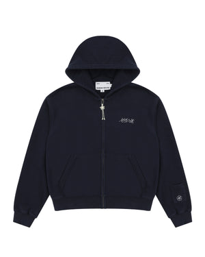 A navy cotton zip-up hoodie by Sundae School featuring front pockets, a small white logo on the left chest, and an embroidered patch with Hangul "Sundae School" on the left sleeve near the cuff. This is the NAVY WASH FLOWER KNOT ZIP UP.