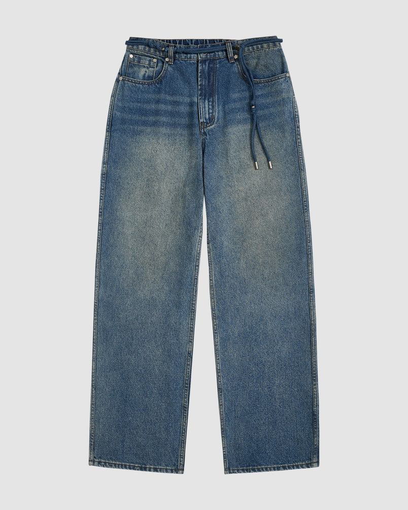 The MEDIUM BLUE FRESHMAN FIT DENIM by Sundae School is a pair of blue relaxed straight-leg jeans with a five-pocket design and drawstring belt, laid flat on a white background.