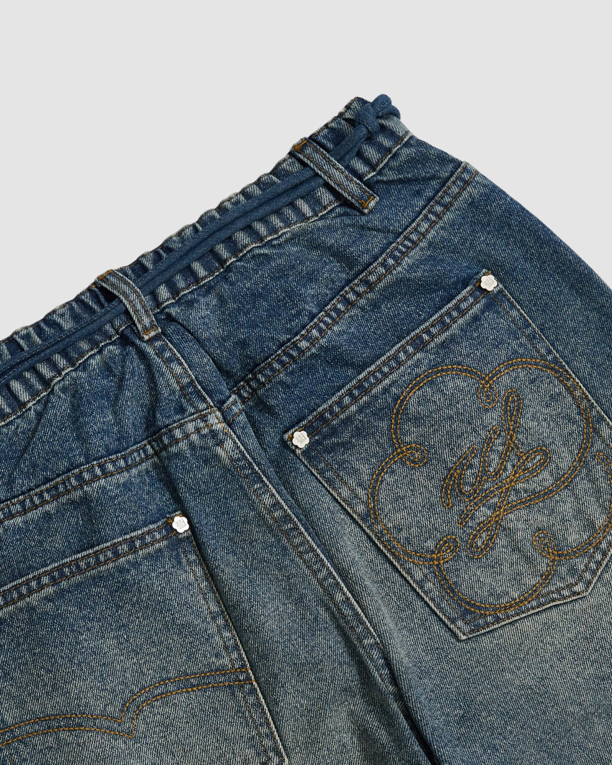 Close-up of the back of Sundae School’s MEDIUM BLUE FRESHMAN FIT DENIM showing two pockets (one embroidered with initials) and an elastic waistband.