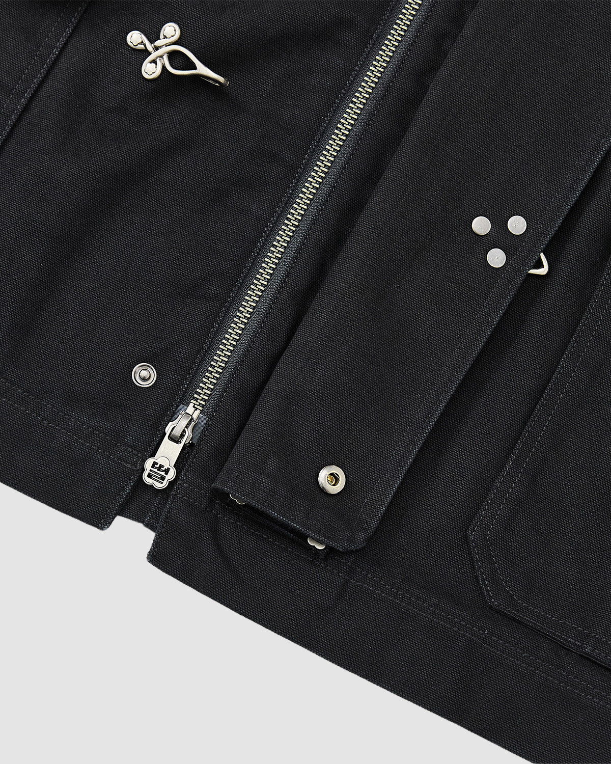 Close-up of the [PRE-ORDER] BLACK FIREMAN CLASP JACKET by Sundae School, featuring a vintage cotton look with metal clasps, visible silver zipper, snap buttons, and multiple seams and pockets for practical workwear style.