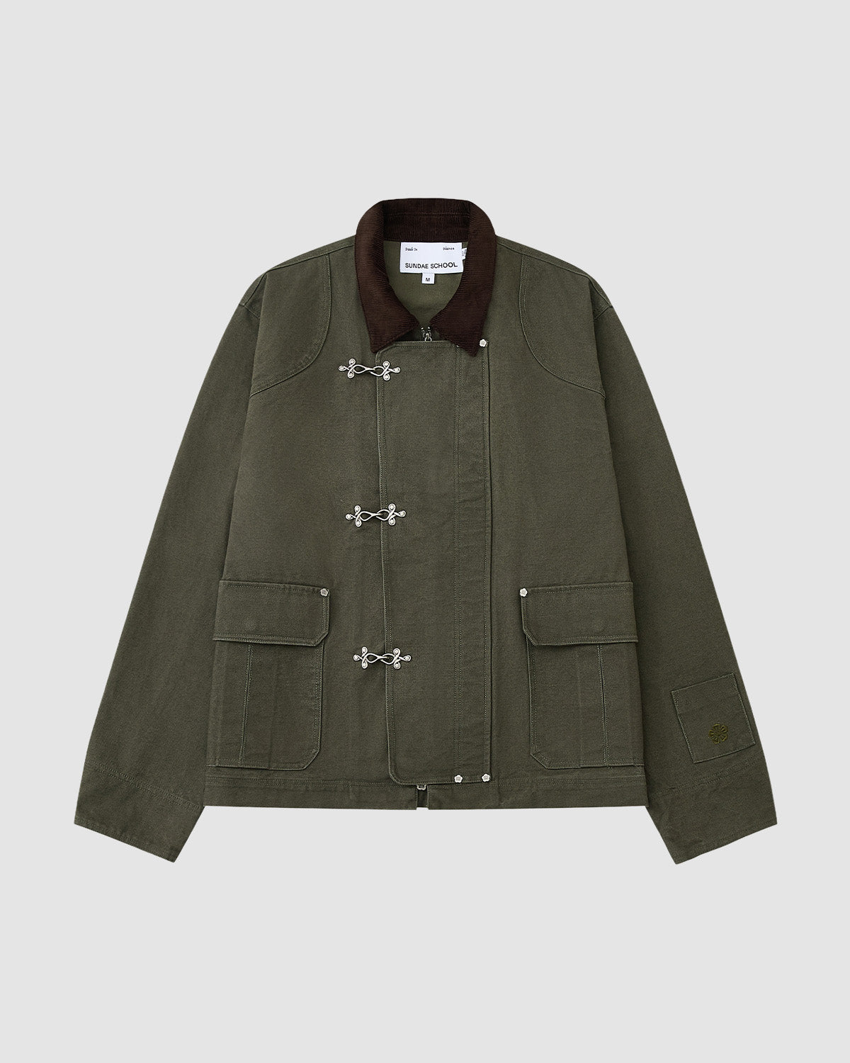 The [PRE-ORDER] OLIVE FIREMAN CLASP JACKET by Sundae School features vintage olive cotton, a dark brown collar, silver clasp closures, two large front pockets, and visible stitching, showcased on a plain light gray background.