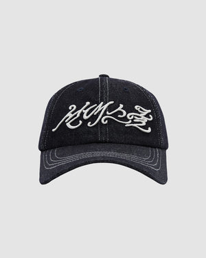 The Sundae School INDIGO FLOWER KNOT CAP is a black denim cap with white graffiti-style Hangul embroidered on the front, shown from the front against a plain gray background.
