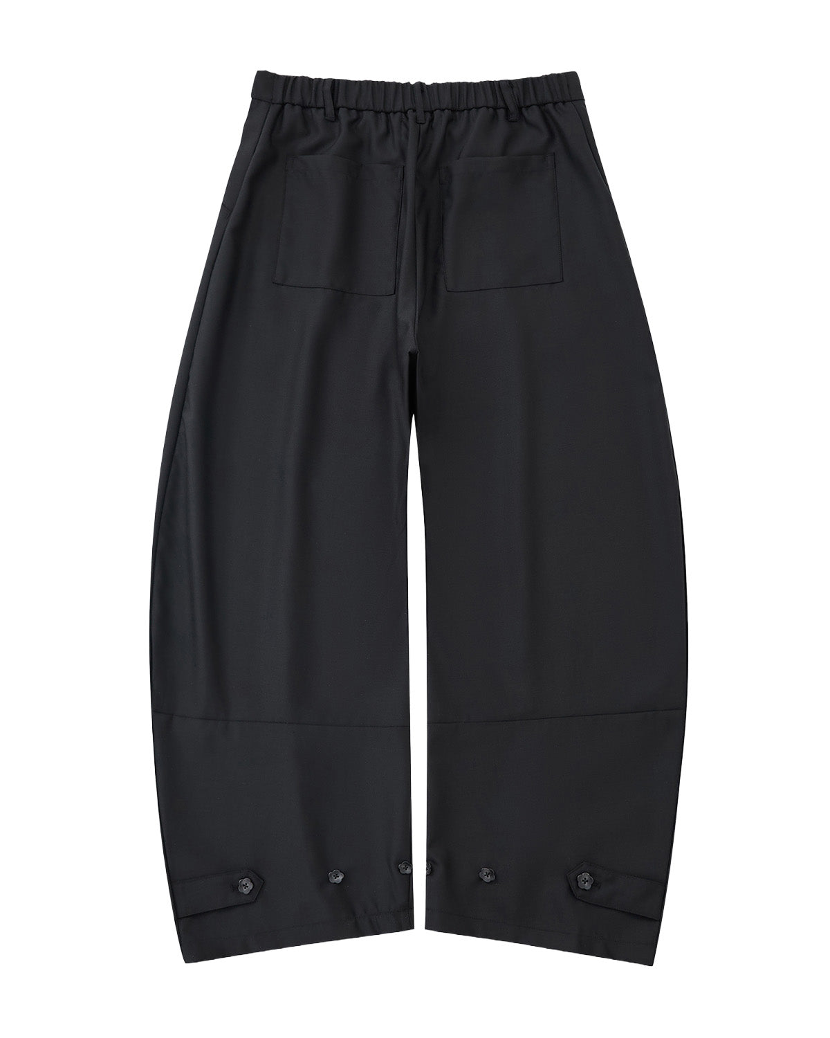 The BLACK PLEATED HANBOK SLACKS by Sundae School are loose-fitting black pants with an elastic waistband, two front patch pockets, and button details at the hems, shown on a light gray background.