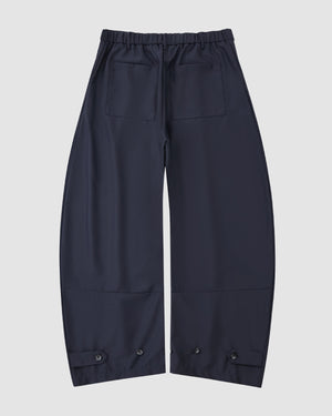 Sundae School NAVY PLEATED HANBOK SLACKS featuring an elastic waistband, two back pockets, and adjustable button cuffs, shown flat on a white background.