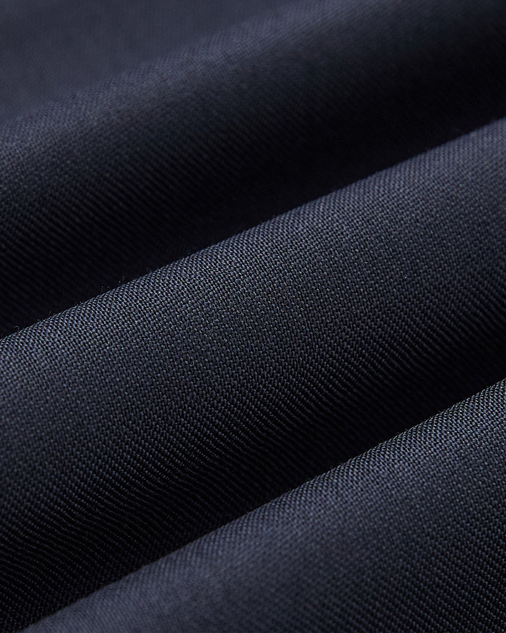 Close-up of finely woven dark blue fabric with soft folds, highlighting the smooth texture of Sundae School's NAVY PLEATED HANBOK SLACKS—ideal for stylish, elegant looks.