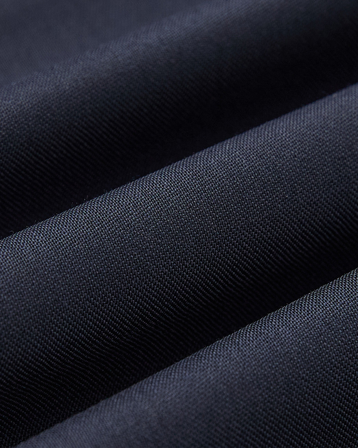 Close-up of finely woven dark blue fabric with soft folds, highlighting the smooth texture of Sundae School's NAVY PLEATED HANBOK SLACKS—ideal for stylish, elegant looks.