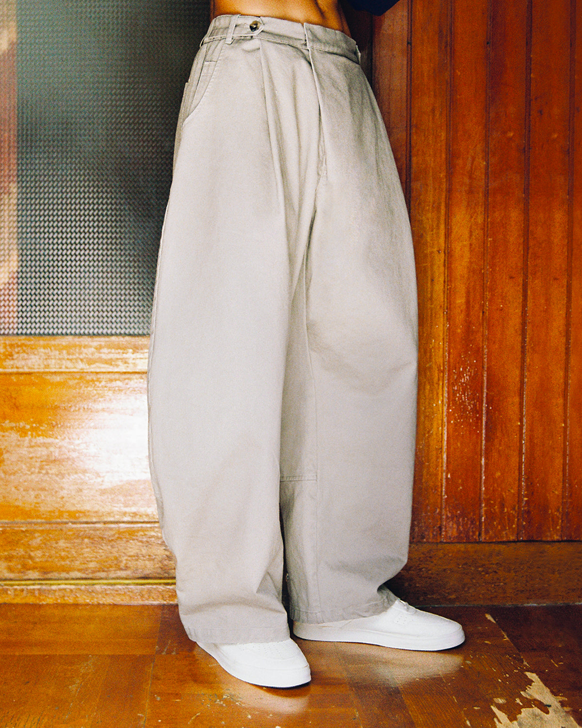 STONE KIEF HANBOK CHINO PANTS in light gray, featuring a high-waisted barrel-fit with a single button closure, worn with white sneakers.