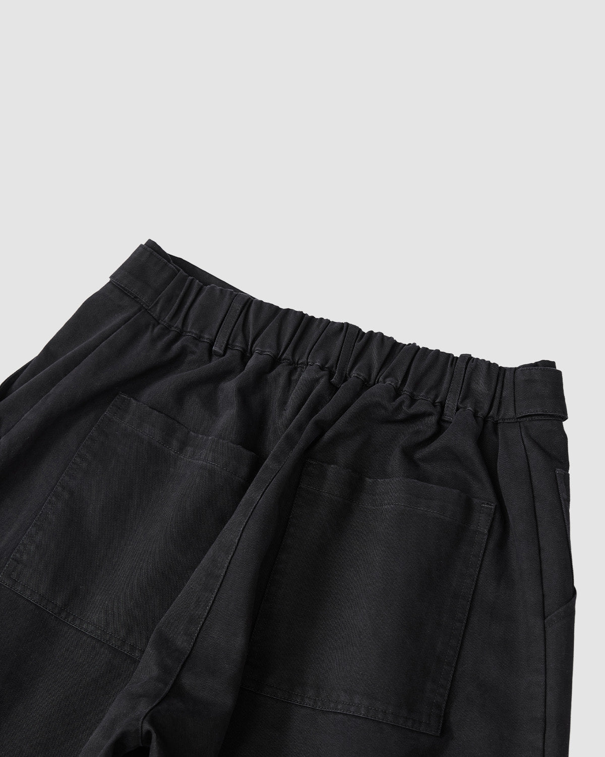 Sundae School's BLACK HANBOK CHINO PANTS feature an elastic waistband, two large back pockets, and a hanbok-inspired silhouette. Made from sturdy, textured fabric, these unisex pants combine comfort and style on a light gray backdrop.