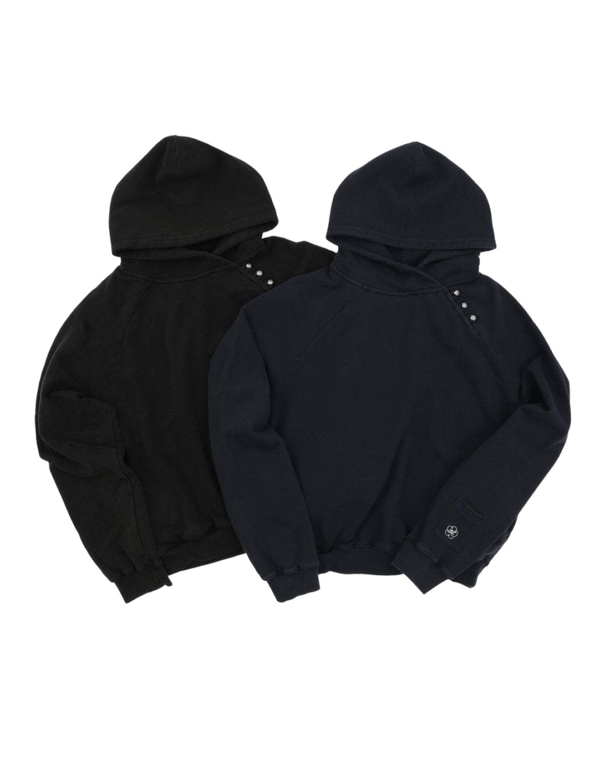 Two BLACK WASH HANBOK HOODIES from Sundae School, one in black and the other in dark navy, are placed side by side. Crafted from cotton, each hoodie is accented with button details near the neckline and features an oversized hood, while the dark navy piece showcases a subtle white logo on its left cuff. These sweatshirts offer a modern take on traditional styles, perfect for fans of the Hanbok Hoodie trend.