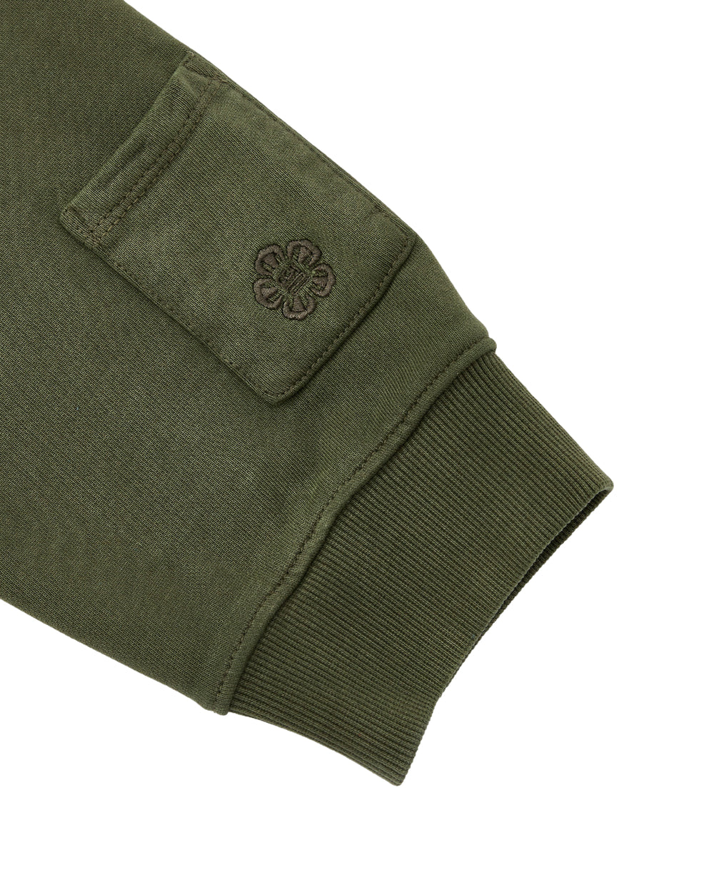 A close-up of the KHAKI HANBOK HOODIE by Sundae School shows an olive green sleeve with a ribbed cuff and a signature sleeve stash pocket adorned with an embroidered flower design.