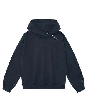 The Sundae School INDIGO WASH HANBOK HOODIE is a black hooded sweatshirt featuring long sleeves with ribbed cuffs and hem, decorative buttons along one shoulder, and a small embroidered detail on one sleeve. Inspired by traditional Hanbok design, this hoodie is finished with Sundae School’s signature sleeve stash pocket for added functionality.