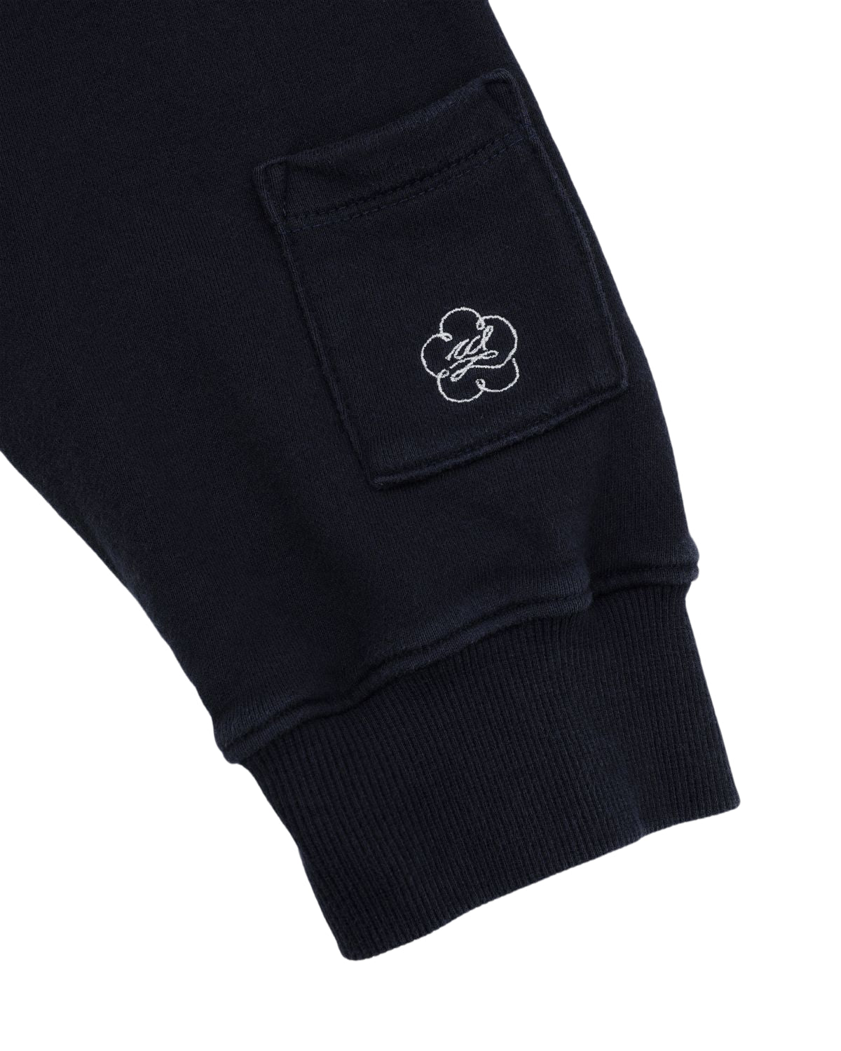 The image displays the cuff and lower sleeve of a Sundae School NAVY WASH HANBOK HOODIE, showcasing a small pocket adorned with an embroidered flower and initials within the design, crafted from custom cotton.