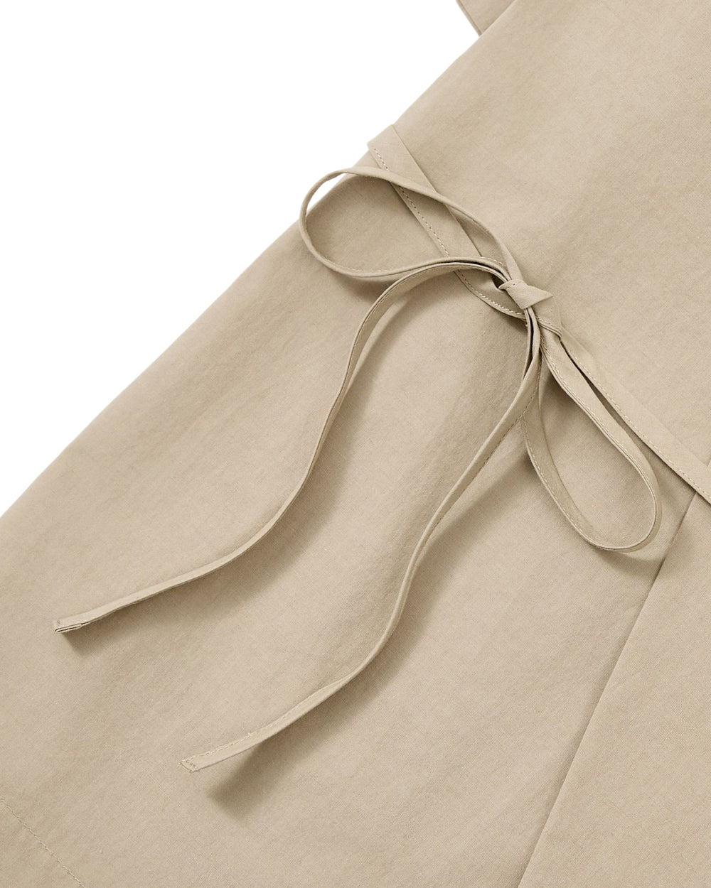Close-up of the WHEAT HANBOK LINEN SHIRT by Sundae School, crafted from a soft cotton-linen blend in beige, featuring a fabric belt tied in a bow at the waist and showcasing its smooth texture and clean stitching.