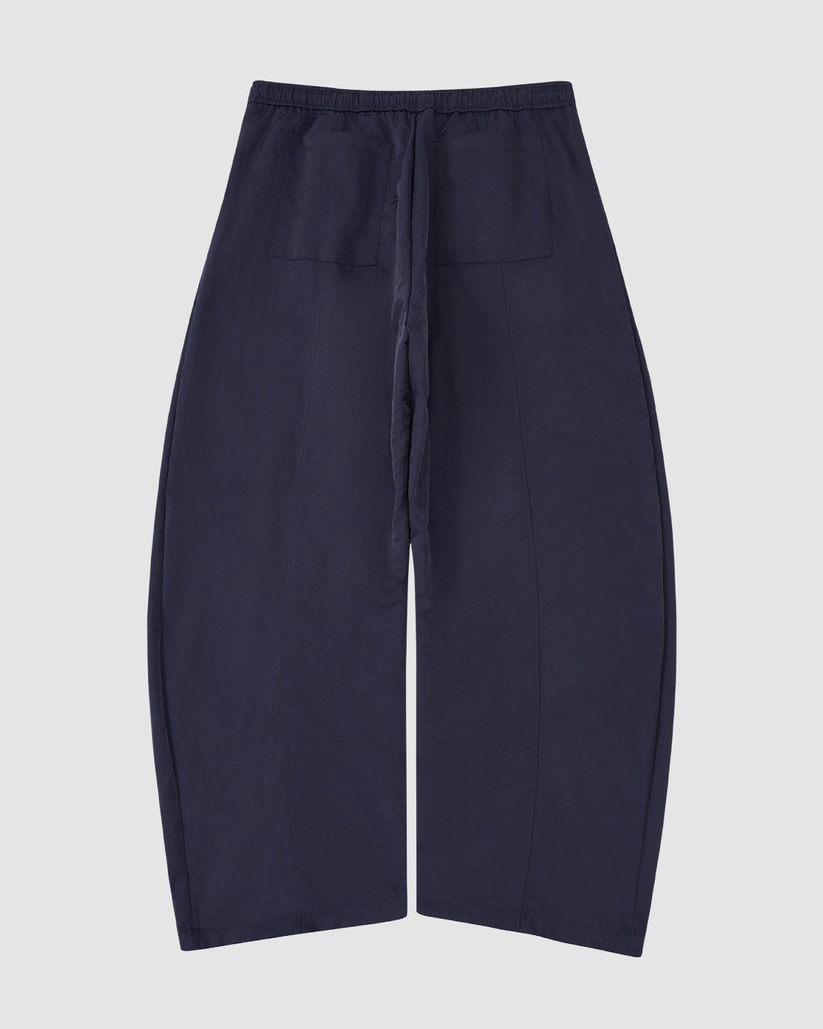 Sundae School NAVY HANBOK BALLOON TRACK PANTS in navy blue nylon with a loose fit, elastic waistband, front drawstring, adjustable hems, and two front patch pockets are shown laid flat on a light grey background.