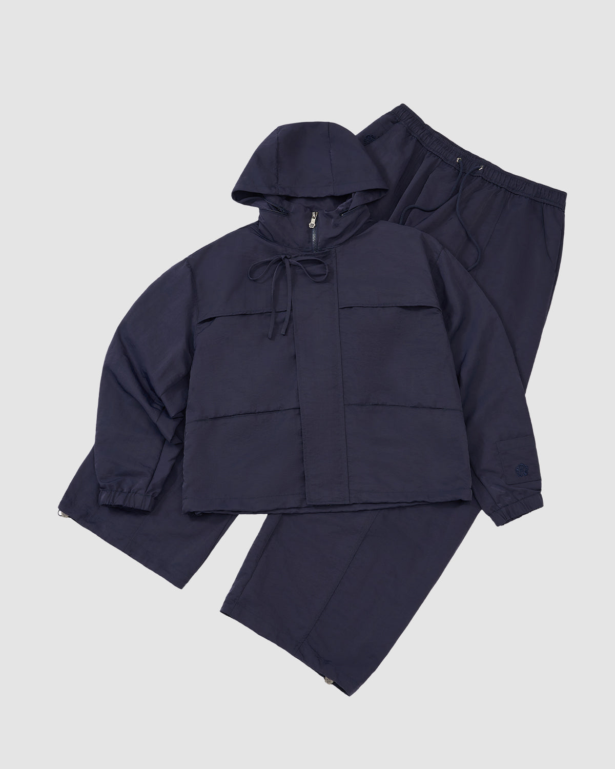 The NAVY HANBOK TRACK JACKET by Sundae School, featuring a hood, custom 떨 zipper pull, and front pockets, is paired with loose-fit elastic waist pants and laid flat on a light background.