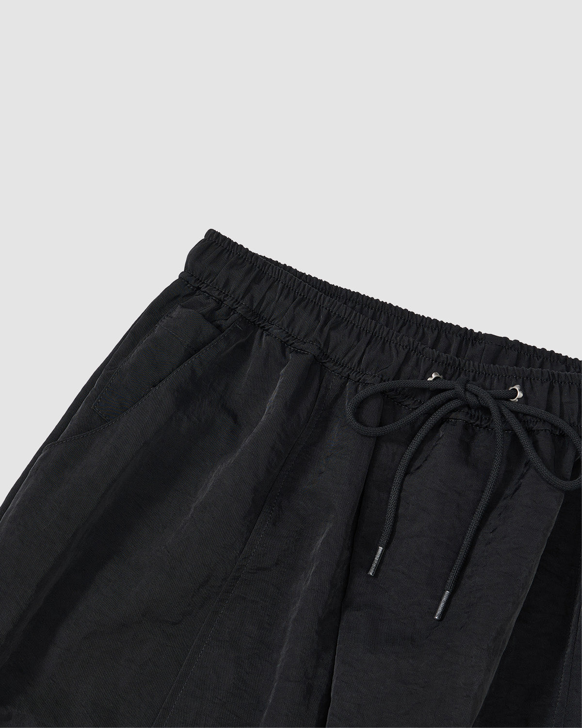 Close-up of Sundae School’s BLACK HANBOK BALLOON TRACK PANTS in technical nylon, featuring an elastic waistband and side pockets, displayed on a light gray background.