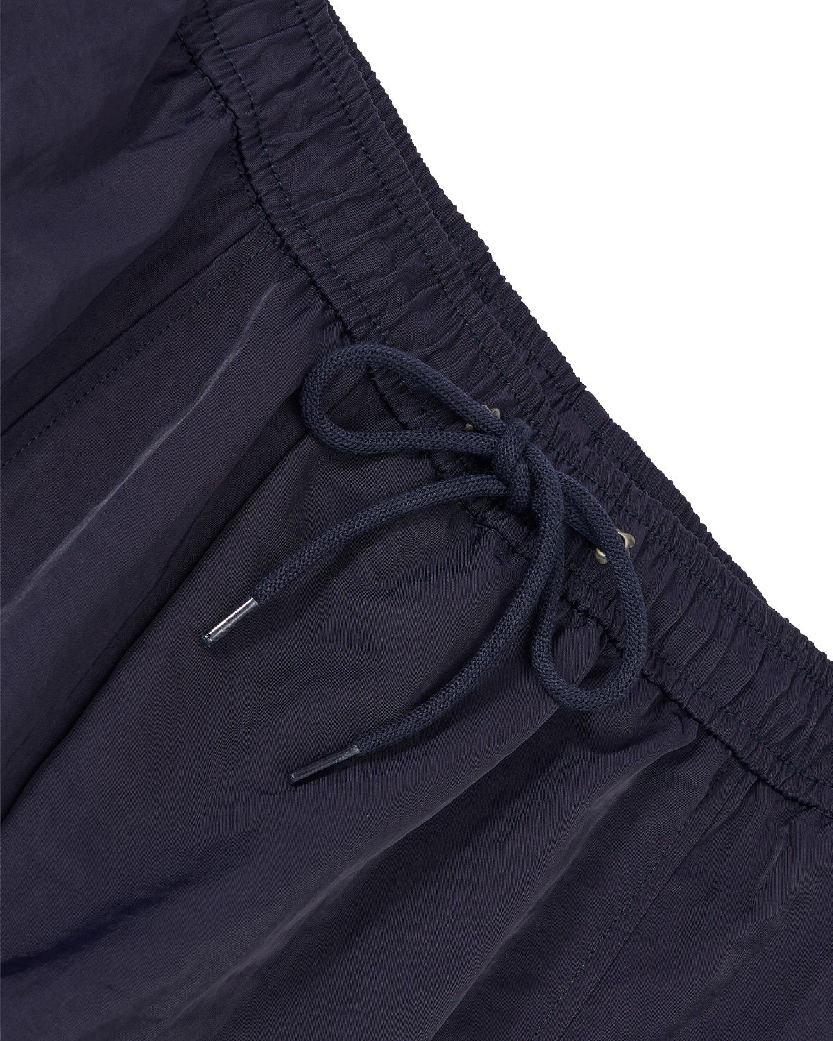 Close-up of dark navy athletic pants showing the elastic waistband, drawstring, and textured fabric against a white background.