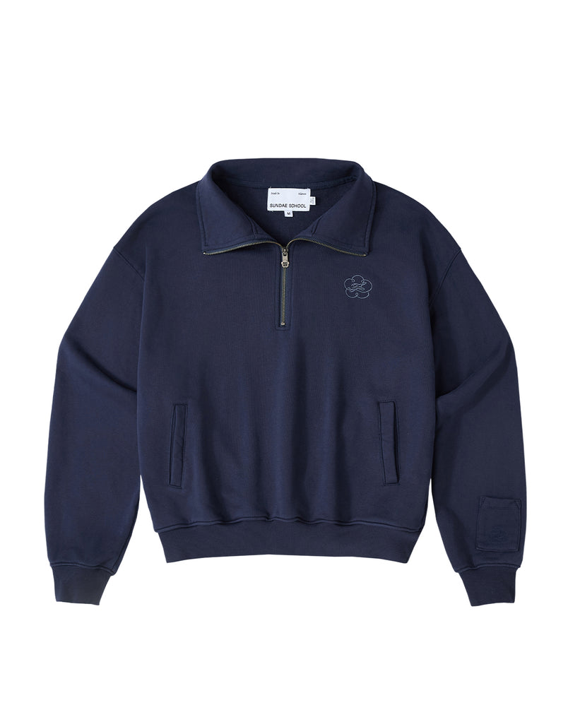 Introducing the NAVY HESTER QUARTER ZIP by Sundae School: An oversized quarter zip pullover in navy, crafted from vintage cotton for lasting comfort. It features a small embroidered Sundae School logo on the chest, two front pockets, ribbed cuffs, a collar, and a discreet stash pocket. The inside label reads Sundae School.