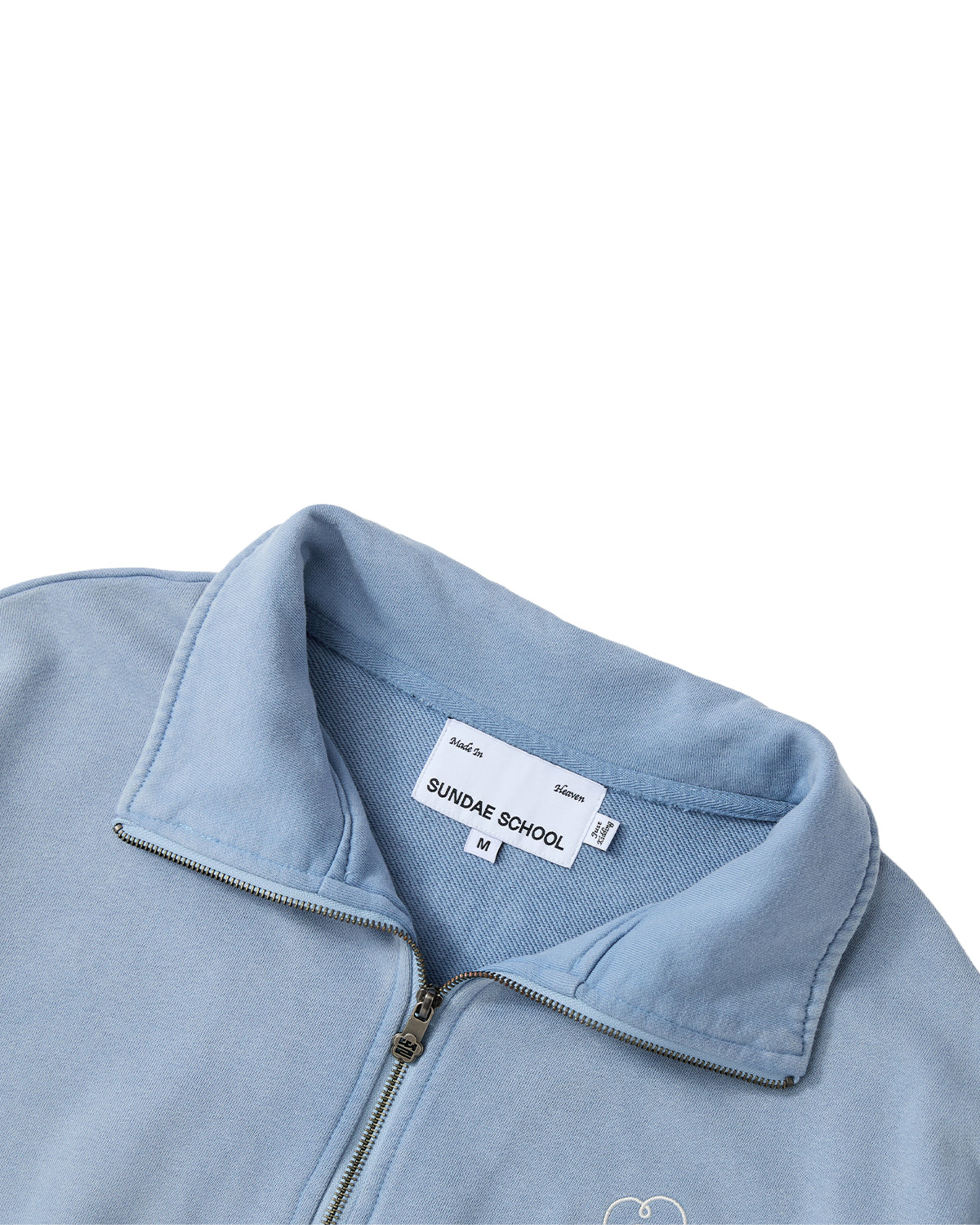 Sky Blue Hester Quarter Zip fleece jacket by Sundae School, featuring a funnel neck collar and partially unzipped to reveal the inside tag with the brand name and M size, shown against a white background.