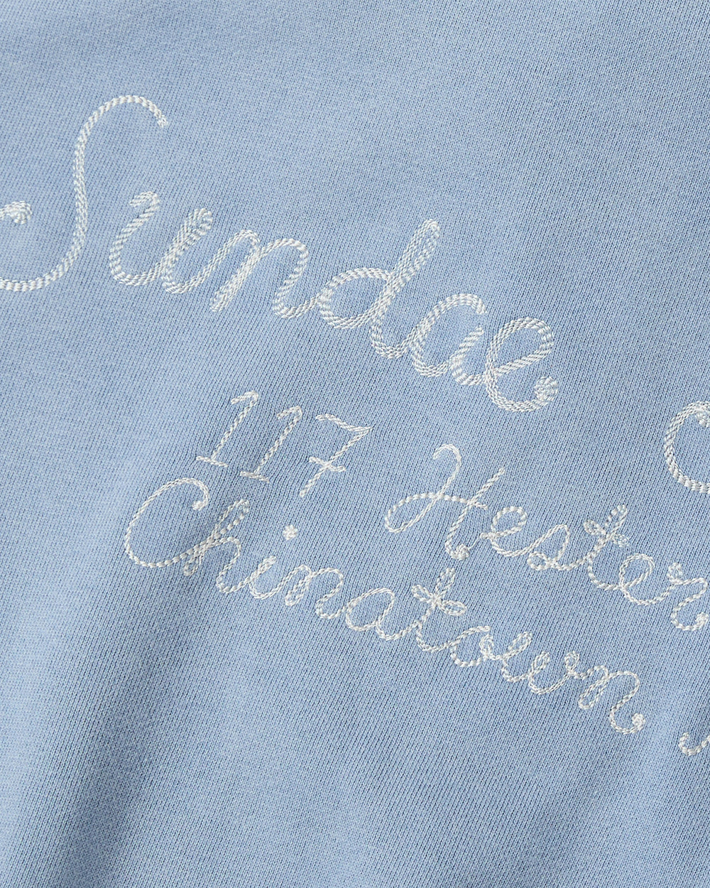 Check out the Sundae School SKY BLUE HESTER QUARTER ZIP—a vintage-inspired cotton pullover in light blue, featuring a funnel neck collar and white embroidered cursive text that reads: Sundae, 117 Hester, and Chinatown.