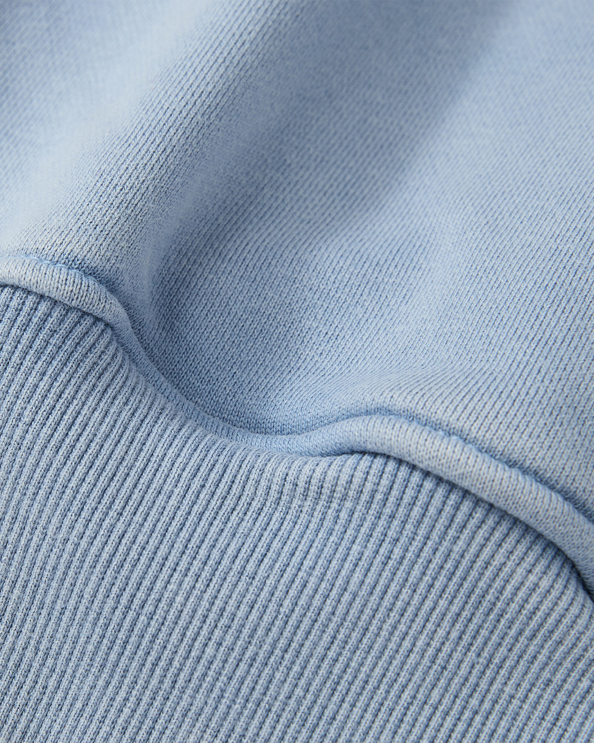 Close-up of the SKY BLUE HESTER QUARTER ZIP by Sundae School, highlighting its ribbed cotton fabric, visible stitching, and soft folds for a detailed view of texture and weave.