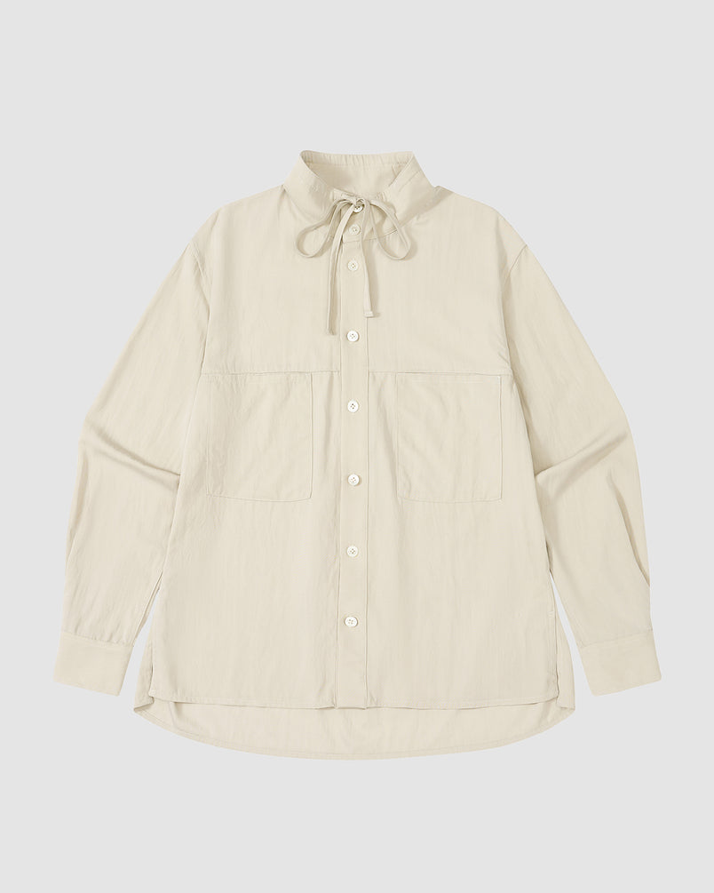 The IVORY HIGH NECK TIE SHIRT by Sundae School is a cream, long-sleeve summer-weight top with a convertible high neck, oversized chest pockets, and a drawstring collar, shown laid flat on a white background.