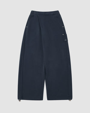 The Sundae School INDIGO WASH WRAP SWEATBAJI features navy blue, Hanbok-inspired wide legs, a high waist, snap buttons at the hips, a side flap pocket, and adjustable drawstring hems on a plain light background.