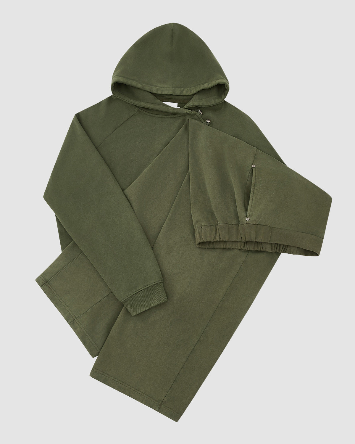 The KHAKI WRAP SWEATBAJI by Sundae School is an olive green hooded sweatshirt with ribbed cuffs and a front pocket, shown laid flat on a white background. One sleeve is stretched across the body, ideal for pairing with wide leg pants.