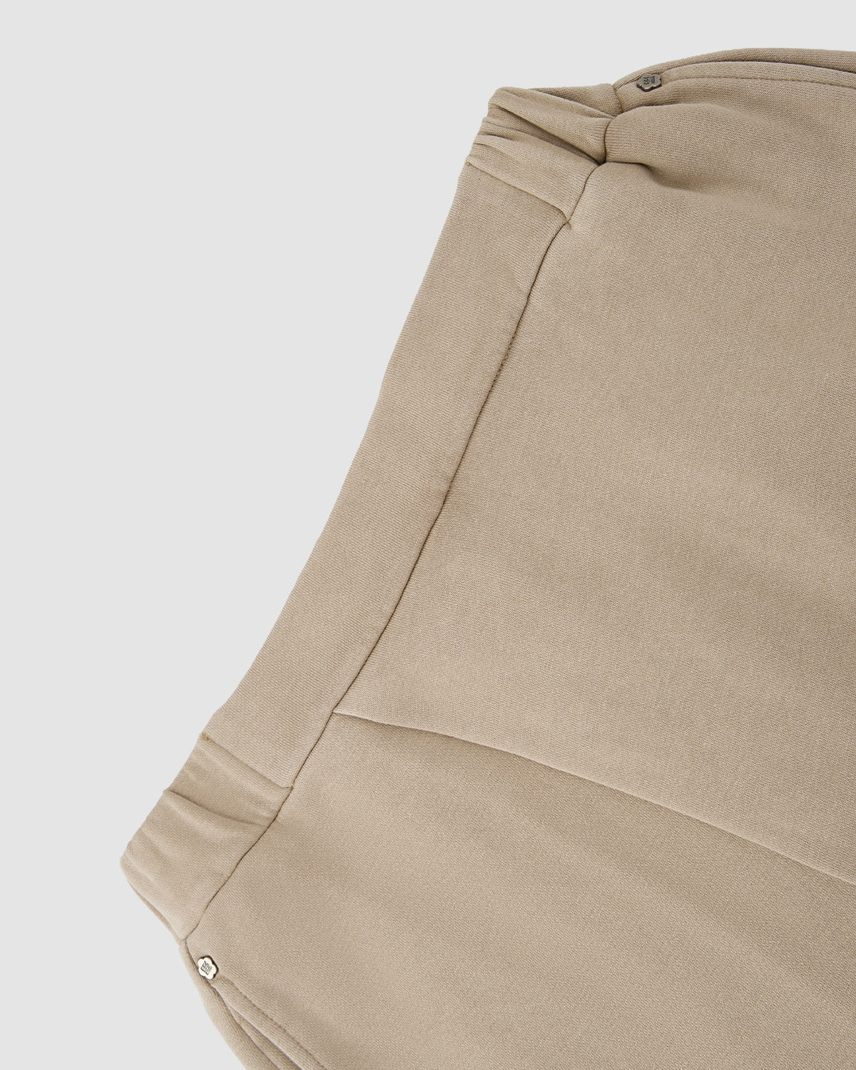Close-up of Sundae School's TAUPE WRAP SWEATBAJI, made from beige 100% cotton with stitched seams and metallic snap buttons in the corners, inspired by Hanbok pants, shown against a white background.