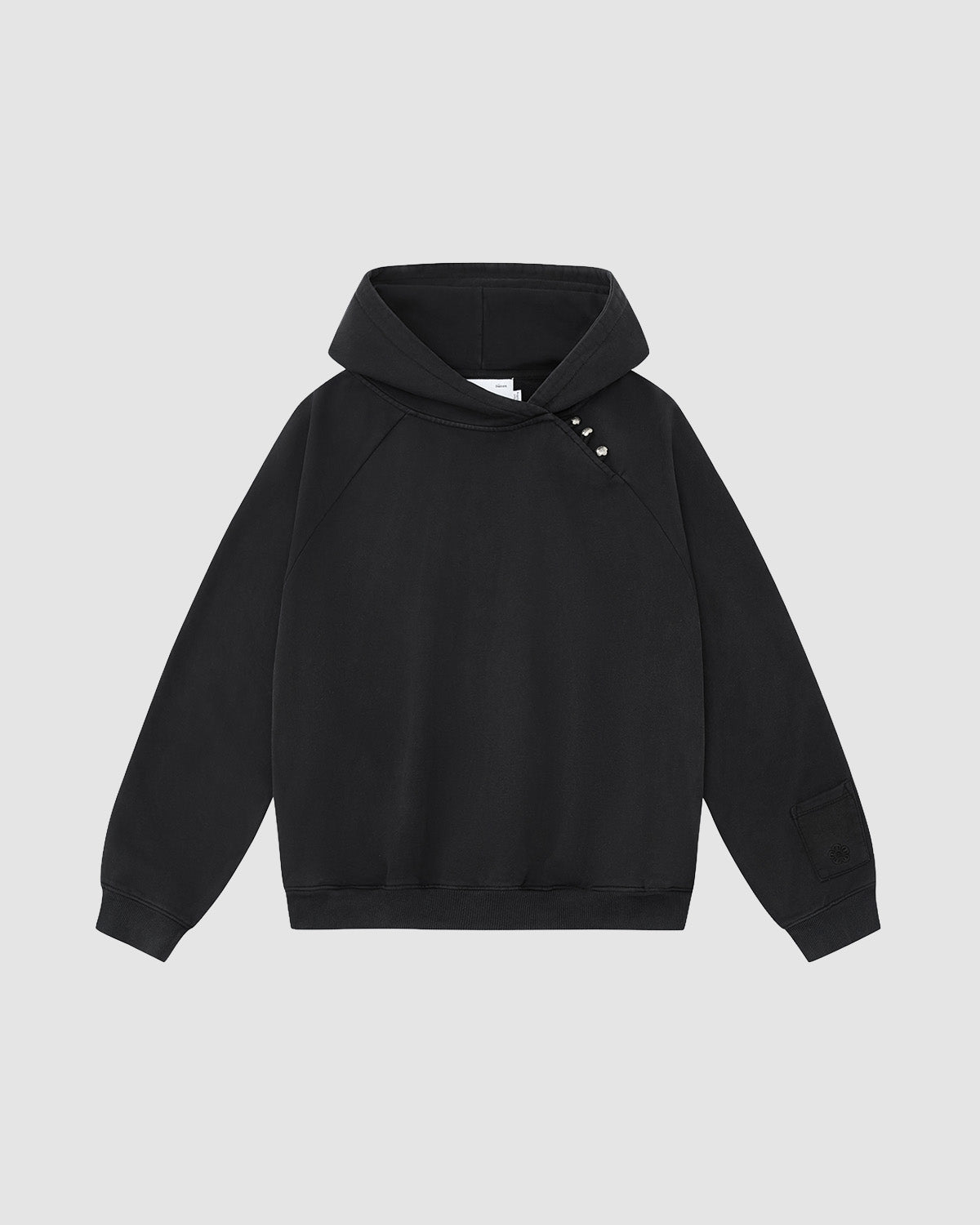 The FADE BLACK HANBOK HOODIE by Sundae School features raglan sleeves, an asymmetric hood closure, three metallic snaps on the left shoulder, and a patch detail on the left sleeve, shown against a light gray background.