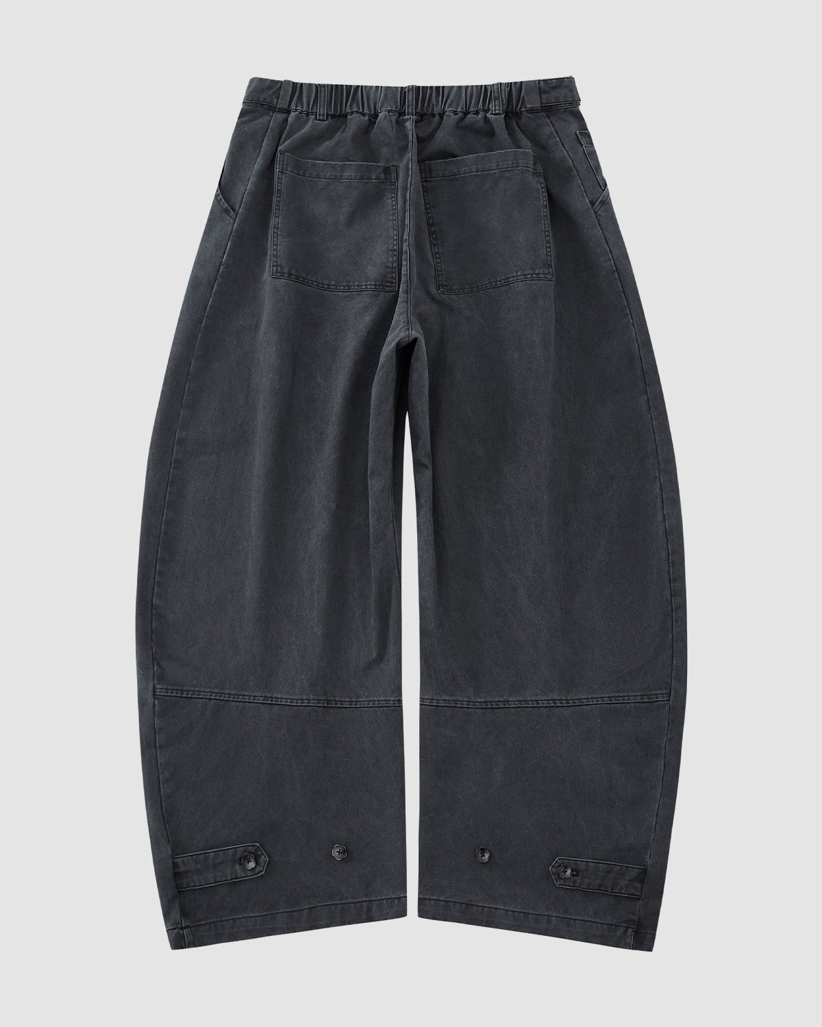 The CHARCOAL HANBOK CHINO PANTS by Sundae School feature a hanbok-inspired silhouette, loose dark gray fabric, elastic waistband, large back pockets, and adjustable buttoned cuffs, displayed flat on a light gray background.