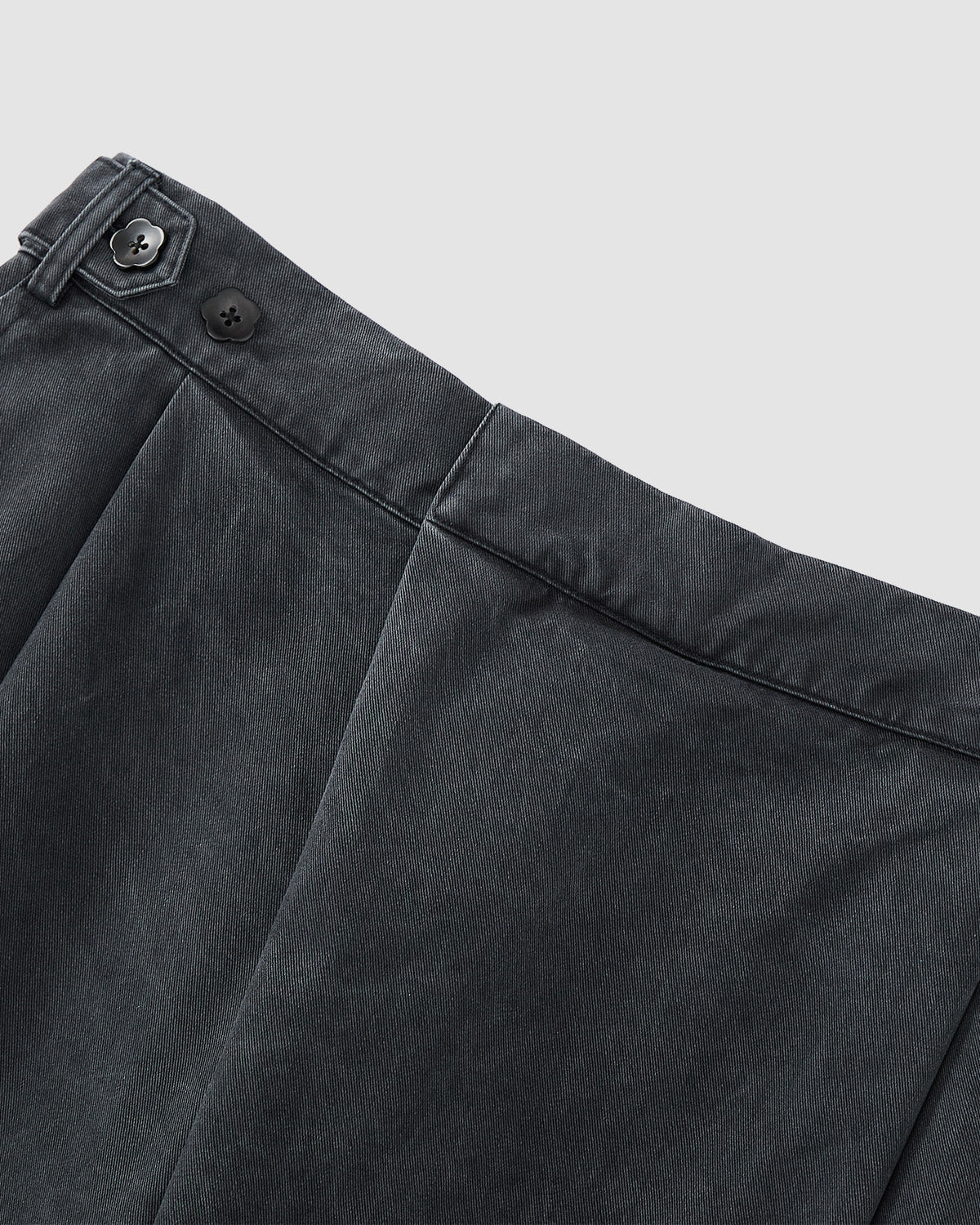 Close-up of the waistband and upper section of Sundae School CHARCOAL HANBOK CHINO PANTS with pleats, belt loops, and two black buttons, highlighting their hanbok-inspired silhouette against a light gray background.