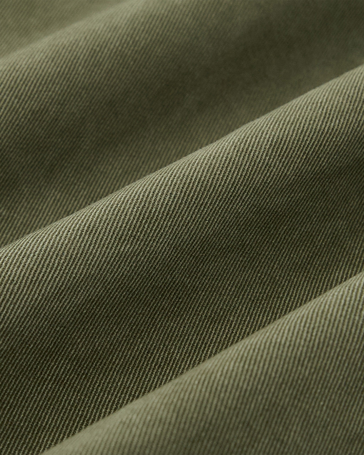 Close-up of olive green, ribbed fabric with diagonal lines and soft folds highlights the unique texture—ideal for Sundae School’s OLIVE HANBOK CHINO PANTS featuring a hanbok-inspired silhouette.