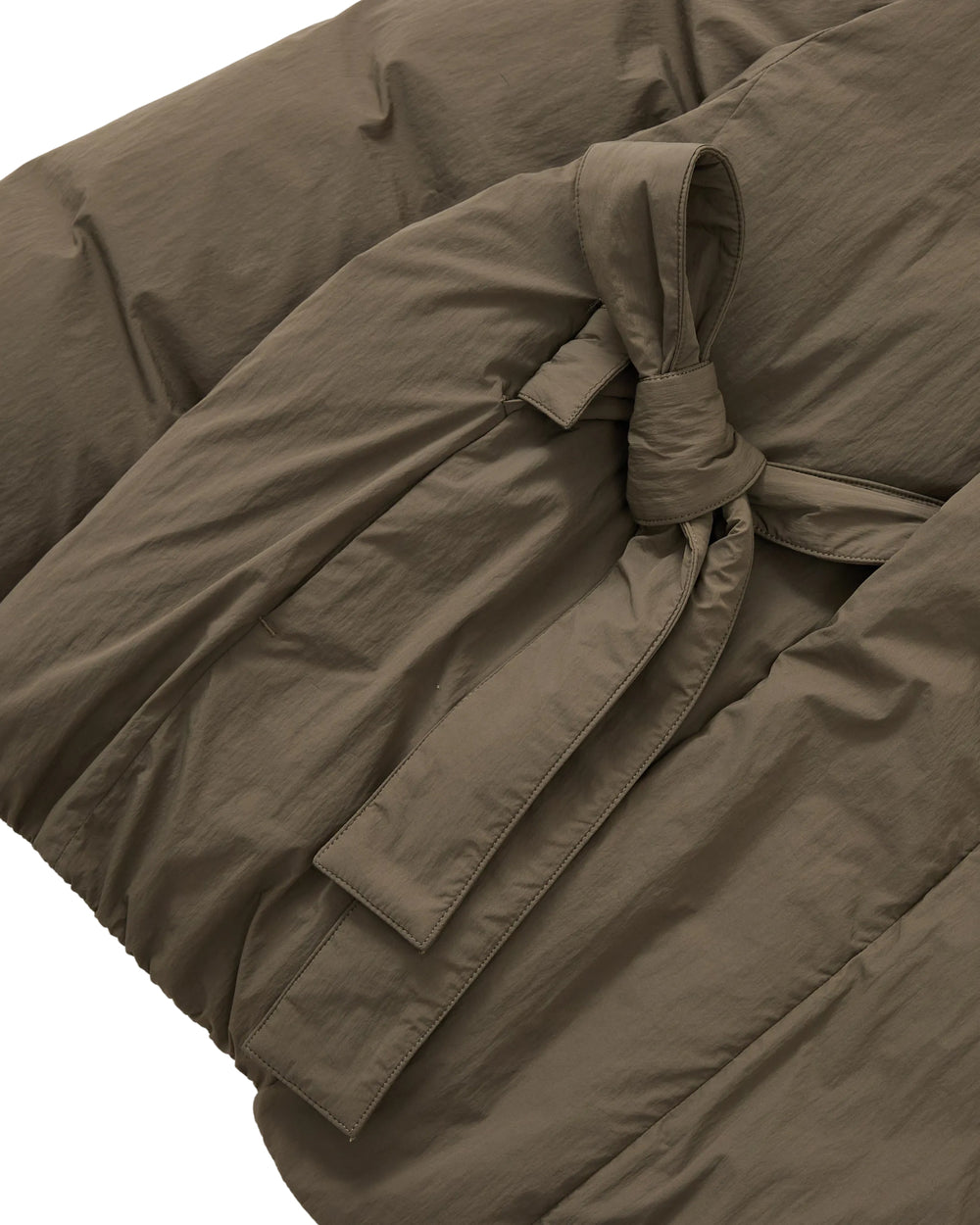 Close-up of the DEEP BROWN IBUL DOWN PUFFER by Sundae School, featuring a fabric belt tied in a knot at the waist and highlighting the textured material and stitching details.