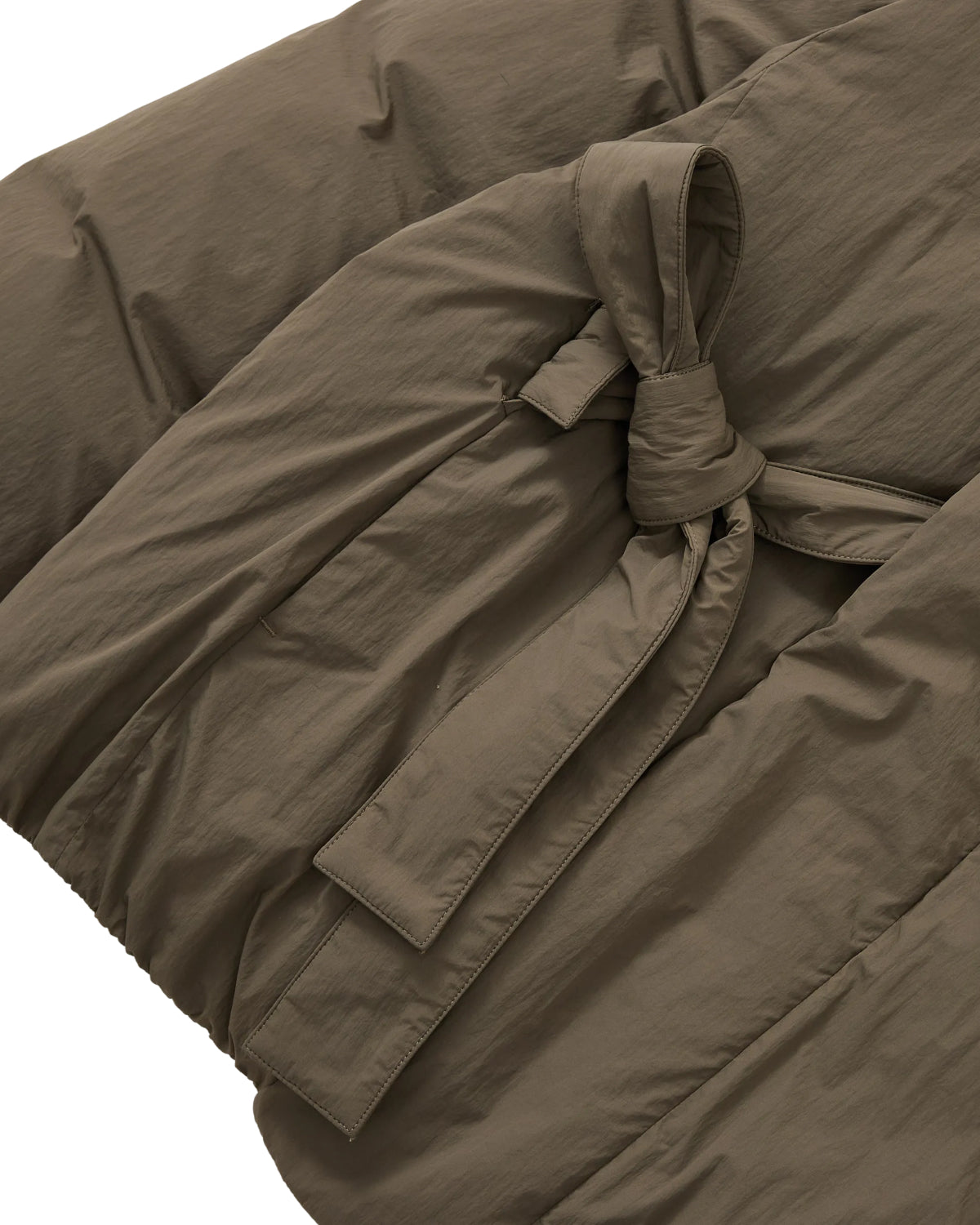 Close-up of the DEEP BROWN IBUL DOWN PUFFER by Sundae School, featuring a fabric belt tied in a knot at the waist and highlighting the textured material and stitching details.