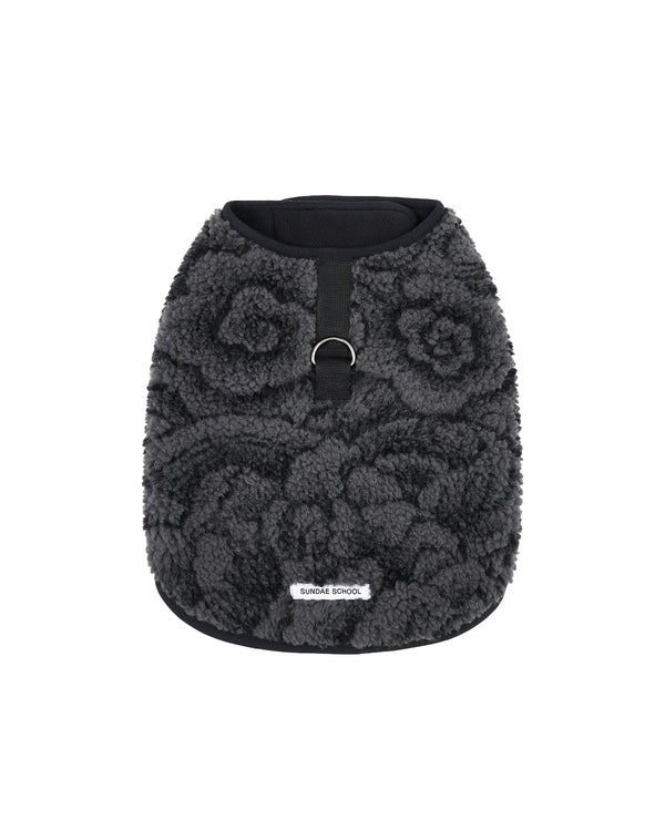 Introducing the BLACK IREZUMI DOGGIE FLEECE by Sundae School—a dark gray, fluffy custom jacquard dog vest featuring a striking floral pattern, a black vertical strap with a metal ring on the back for easy leash attachment, and a small white SUNDAY SCHOOL label at the hem. This adjustable pet jacket keeps your pup both comfortable and stylish on every adventure.