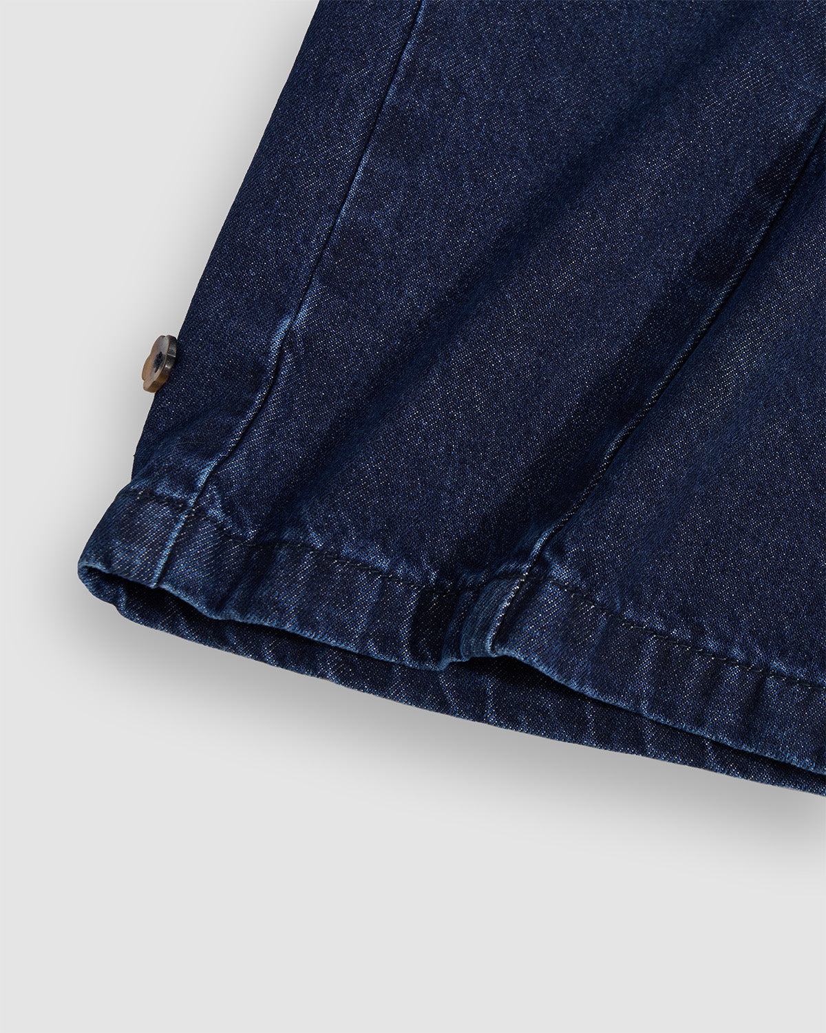 Close-up detail of indigo fade hanbok denim hem showing gathered elastic ankle cuffs with silver snap button closures, demonstrating adjustable hem construction