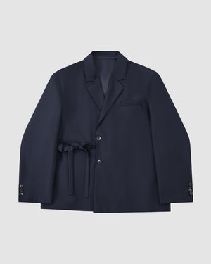 The Sundae School NAVY DOUBLE DUTY BLAZER, a navy wool blend with notched lapel, front buttons, chest pocket, and hanbok-inspired fabric belt at the waist, is displayed flat on a light gray background.