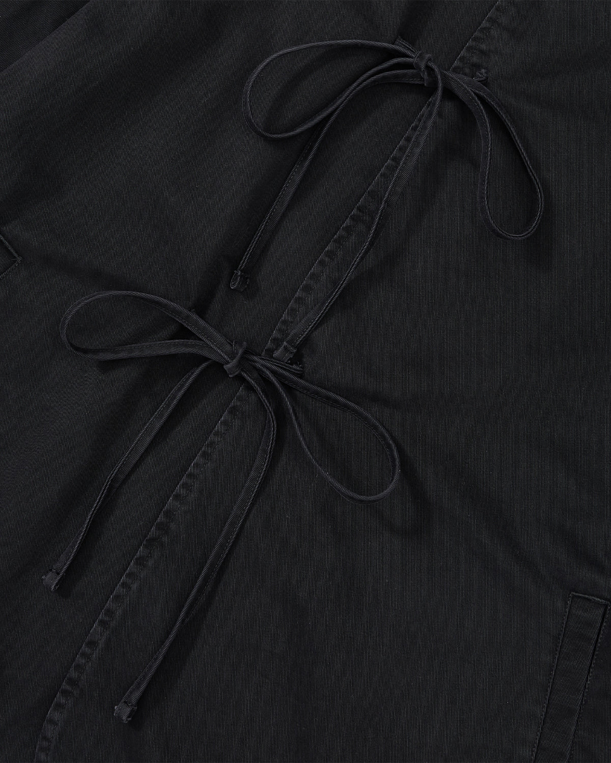 Close-up of the Sundae School BLACK JEOGORI TIE JACKET, showcasing a black fabric with double goreum ties, two diagonal drawstring bows, visible seams, and subtle texture.
