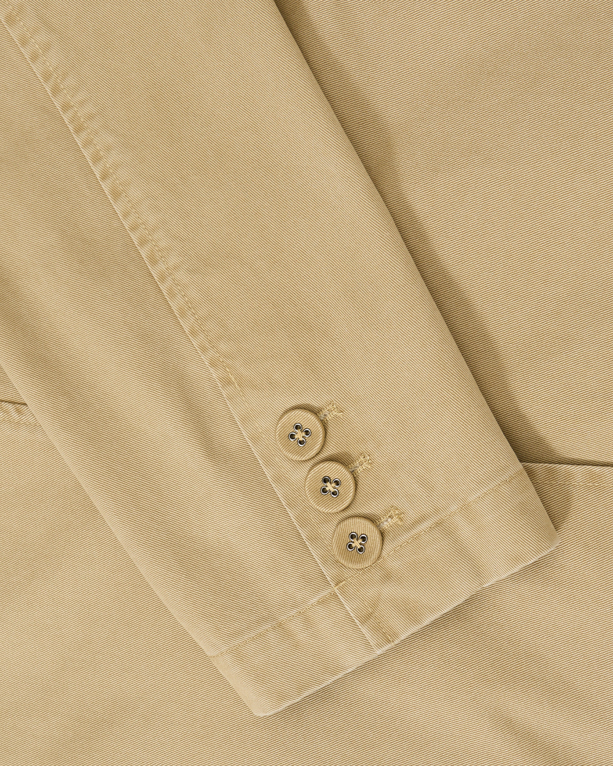 Close-up of the TAN JEOGORI TIE JACKET by Sundae School, featuring a beige sleeve in summer suiting fabric with three tan buttons, detailed stitching, and visible buttonholes against matching fabric.