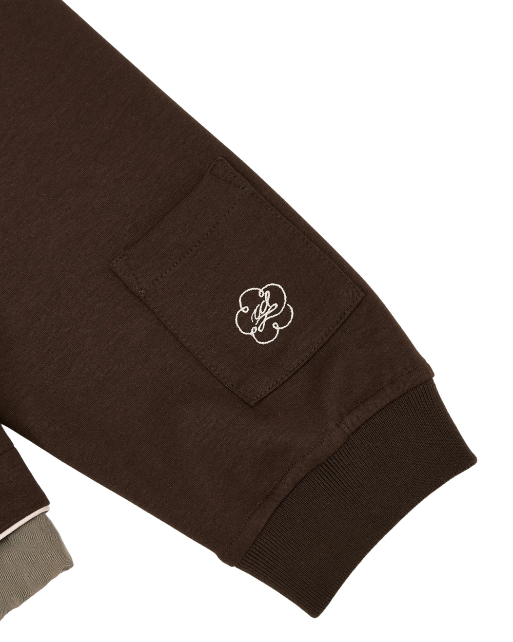 Introducing the BROWN PALISADE PARK TRACK JACKET from Sundae School—a brown long sleeve jacket with a small side pocket, detailed with white chain-stitch embroidery. The sleeves are finished with ribbed cuffs.