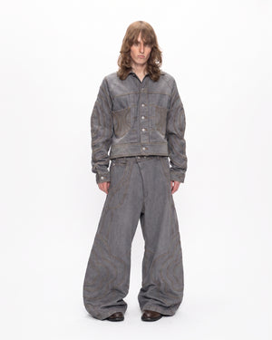 A person with long brown hair wears Sundae School's JOONIVERSE JEANS GREY and a grey denim jacket, standing against a plain white background.